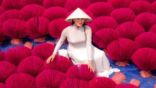 Vietnam girl in traditional white dress with incense drying outdoors