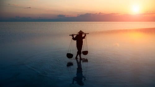 Farmer carrying baskets on the water in Cambodia